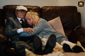 Uma imagem emocionante de fotografia de casamento que captura o amor e o vínculo entre os avós, dormindo pacificamente e aconchegados em um sofá aconchegante em sua casa em Londres.